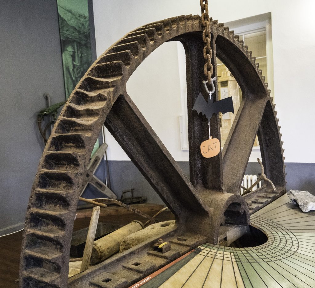 Large iron wheel with gear teeth around the rim, on display at East Pool Mine in Cornwall