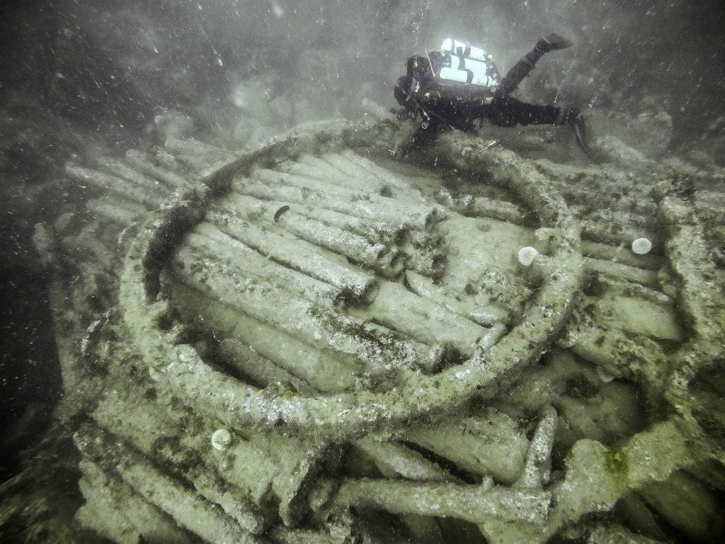 A diver swimming over the large wheel at the centre of the cargo mound