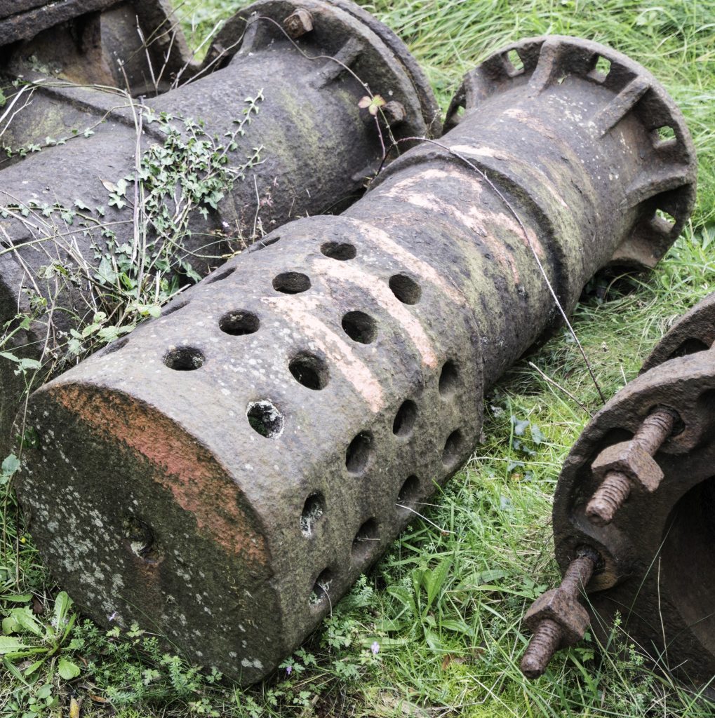 Two large iron pipes sitting on the grass at East Pool Mine