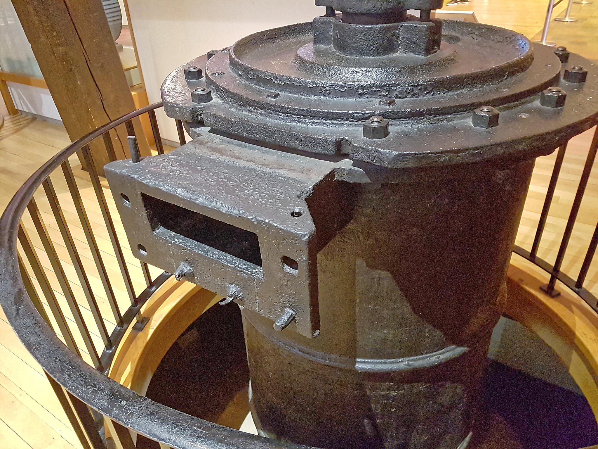 Photograph of a 33 inch engine cylinder on display in the Science Museum, London. It is painted black, is surrounded by a protective railing, and has a rectangular steam port very similar to that found on the Wheel Wreck cylinder fragment C1.